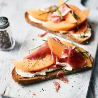Toast integral cu prosciutto crudo, crema de branza cu smochine, chives si mix de salata
