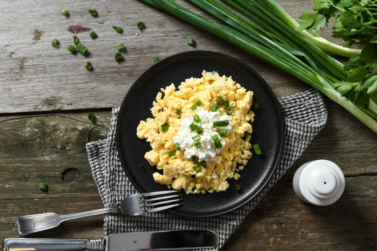 Scrambled eggs garnisite cu branza de capra, chives si crackersi integrali